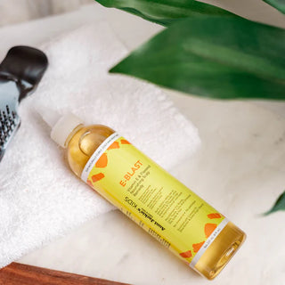 Bottle of Bottle of Aunt Fannie's Kids E-Blast Vitamin E & Flaxseed Nourishing Scalp Remedy on a white towel with green leaves in the background