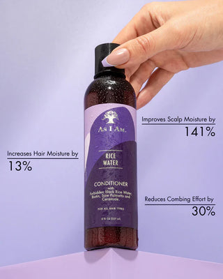 Hand holding a bottle of As I Am Rice Water Conditioner against a light purple background