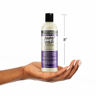 Bottle of Aunt Jackie's Power Wash Shampoo held in a hand with a measurement label on a white background