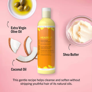 HEADS UP shampoo bottle with ingredients like Extra Virgin Olive Oil, Coconut Oil, and Shea Butter on a pink background.