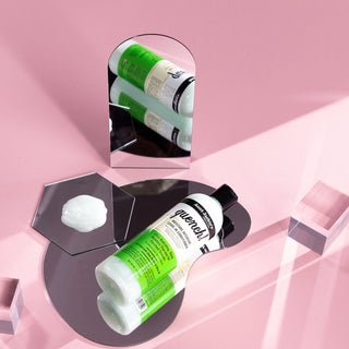 Two bottles of Guerlain products on a pink background with geometric shapes.