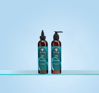Two bottles of As I Am Shampoo and Conditioner on a light blue background