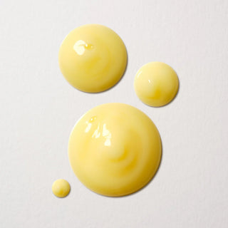 Yellow droplets of Boucleme hair care product bottle on a light gray background