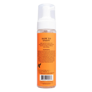 Hair product bottle with orange label and white cap on a white background