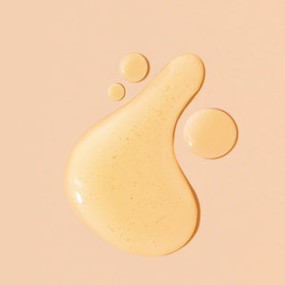 Yellow liquid (oil) droplet and spread on a beige background
