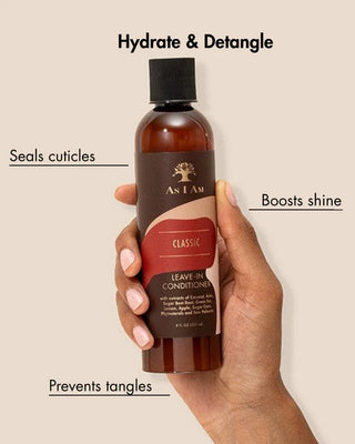 Hand holding a bottle of As I Am leave-in conditioner with text highlighting benefits on a beige background