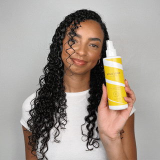woman applying curl defense spray on a white background