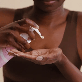 Person applying lotion to their hand with a bottle in the background