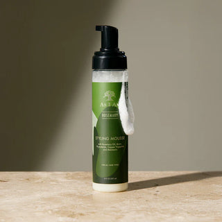 Bottle of styling mousse with green label on a wooden surface
