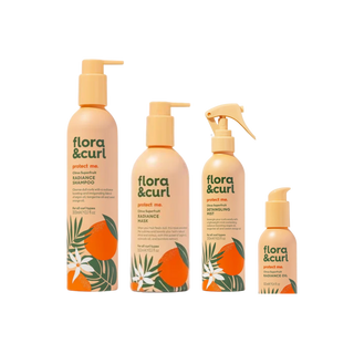 Four Flora & Curl haircare products in a coordinated peach and orange color scheme, including shampoo, conditioner, styling mist, and two small bottles, shown on a plain white background.