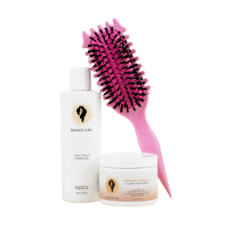 Bounce Curl hair care products including a bottle, a jar, and a pink brush on a pink background